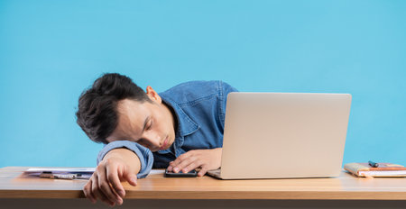 Asian businessman dropped his head on the table because of the pressure at workの写真素材