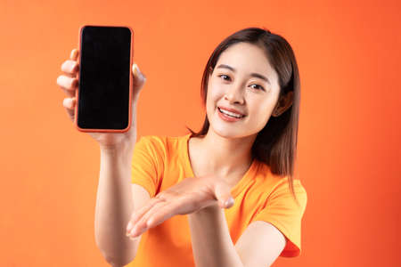 Young Asian woman holding smartphone with empty screenの写真素材