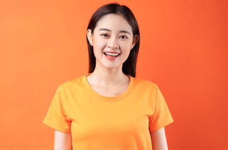 Image of young Asian woman wearing orange t-shirt on orange backgroundの写真素材