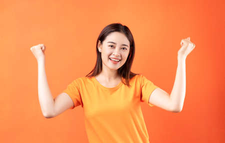 Image of young Asian woman wearing orange t-shirt on orange background