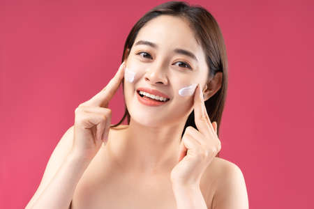 Cheerful Asian woman with beautiful skin using lotionの写真素材