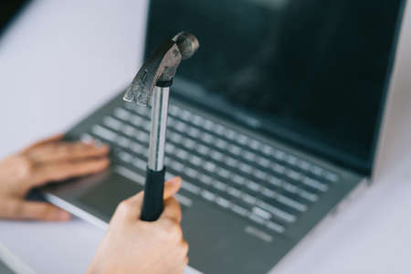 Asian woman holding hammer to beat the laptopの写真素材