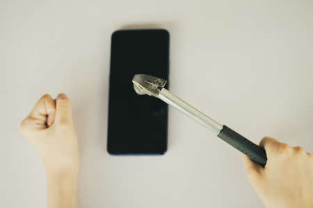 Asian woman using hammer to break her smartphone
