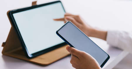 Asian woman using smartphone and tablet with blank screen