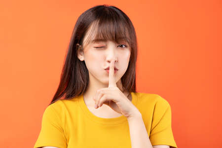 Image of young Asian girl wearing yellow t-shirt on orange background
