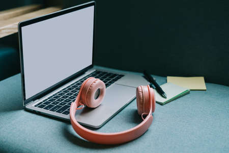 Image of laptop with white screen and pink headphones besideの写真素材
