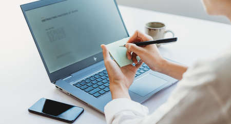 Cropped image of Asian businesswoman noted information from laptop