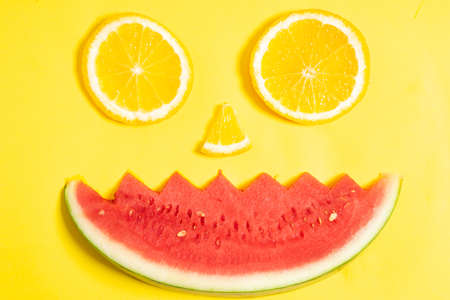 Orange slices and watermelon pieces arranged in the shape of a human faceの写真素材