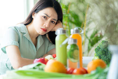 Young Asian woman holding a bag of vegetables on purple backgroundの写真素材