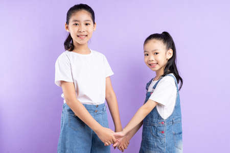 Portrait of two Asian girls on purple backgroundの写真素材