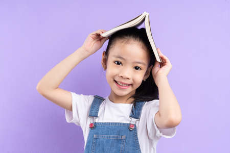 Portrait of Asian child holding book on green backgroundの写真素材
