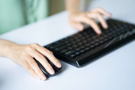 Asian woman using mouse and keyboard to work