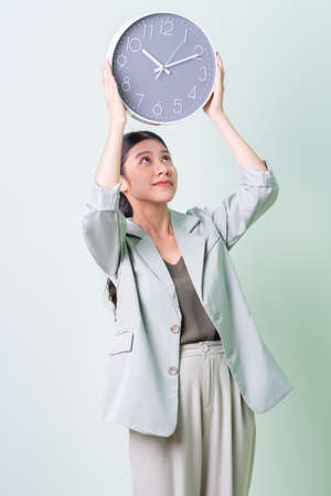 Young Asian businesswoman holding smartphone on green background