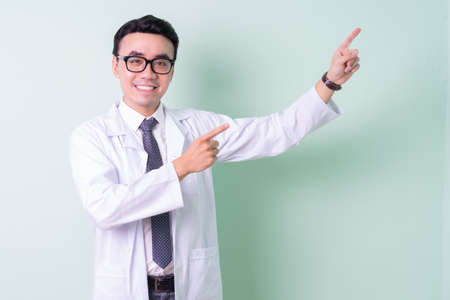 Asian doctor standing on green backgroundの写真素材