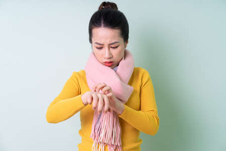 Beautiful young Asian woman wearing sweater on green background