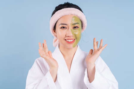 Young Asian woman wearing bathrobe on blue backgroundの写真素材