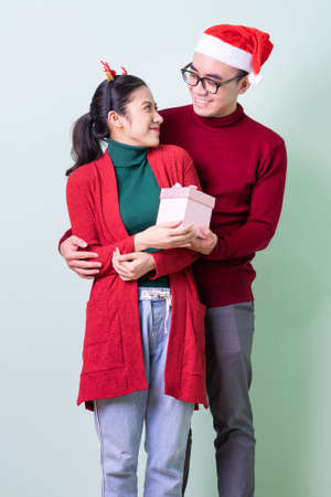 Young Asian couple posing on green background with christmas conceptの写真素材