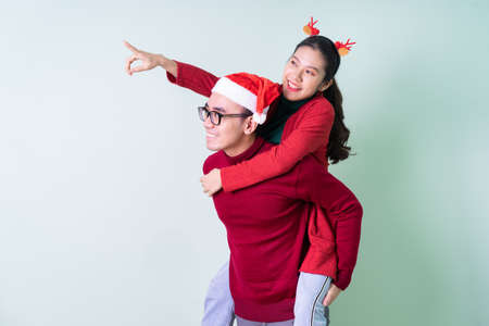 Young Asian couple posing on green background with christmas conceptの写真素材