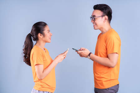 Young Asian couple wearing orange t-shirt on blue background