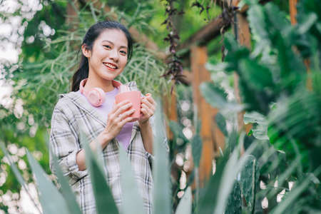 Young Asian woman drinking tea in the gardenの写真素材