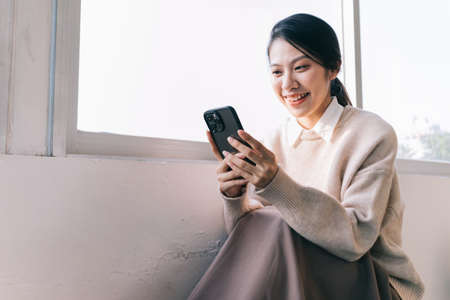 Young Asian woman using smartphone at homeの写真素材