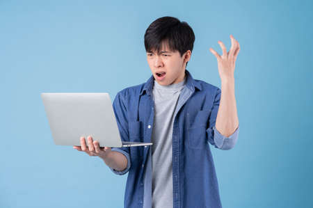 Young Asian man posing on blue background