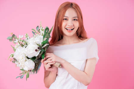 Young Asian bride posing on pink background