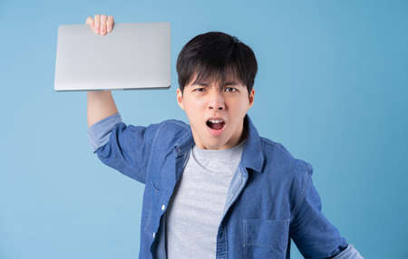 Young Asian man posing on blue backgroundの写真素材