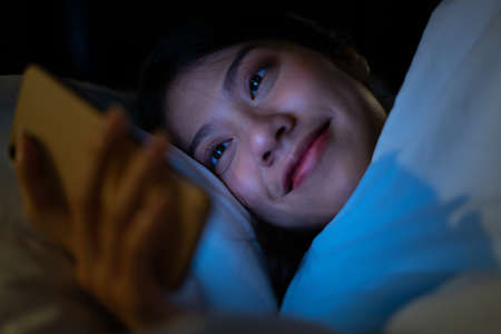 Young Asian woman using smartphone at midnight