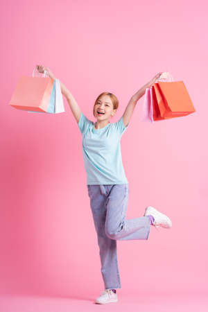 Young Asian woman holding shopping bag on pink backgroundの写真素材