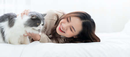 Young Asian woman playing with cat at homeの写真素材