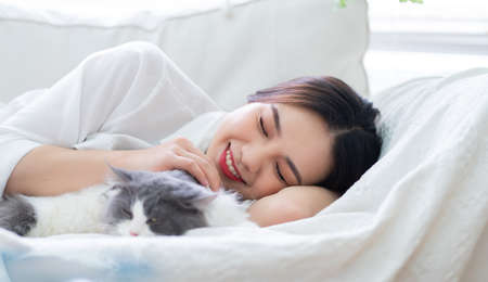 Young Asian woman playing with cat at homeの写真素材