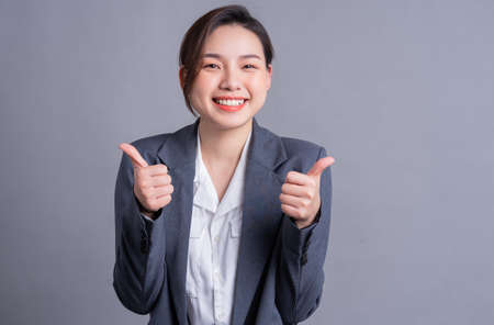 Young Asian business woman standing on gray backgroundの写真素材