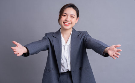 Young Asian business woman standing on gray backgroundの写真素材