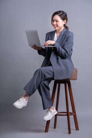 Young Asian businesswoman holding smartphone on gray backgroundの写真素材