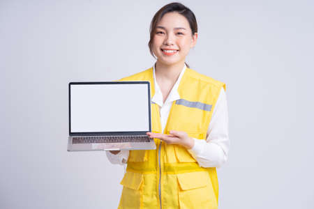 Young Asian businesswoman holding smartphone on gray background