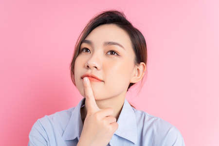 Image of young Asian girl holding smartphone on pink backgroundの写真素材