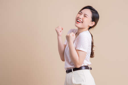 Image of young Asian girl holding smartphone on pink backgroundの写真素材