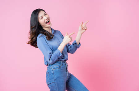 Full length image of young Asian woman wearing dress on blue background