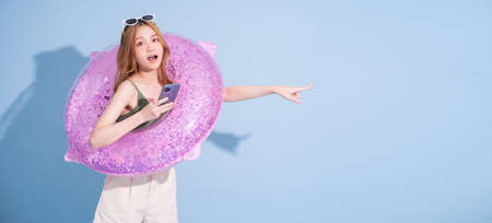 Image of young Asian girl holding swimming float on blue background, summer vacation conceptの写真素材