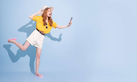 Image of young Asian girl holding swimming float on blue background, summer vacation concept