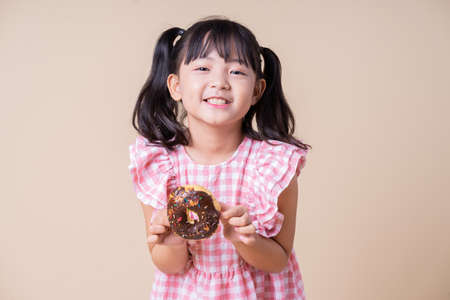 Image of Asian child eating cup cake on backgroundの写真素材