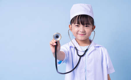 Image of Asian child wearing doctor uniform on blue backgroundの写真素材