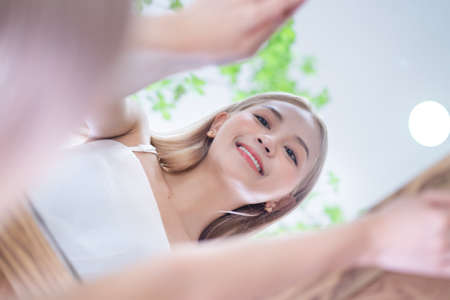 Young Asian woman applying lipstick in front of mirror
