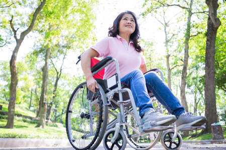 Image of middle-age Asian woman sitting on wheelchair