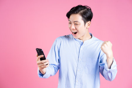 Young Asian man holding dumbbell on background
