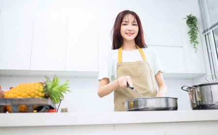 Image of young Asian woman in the kitchenの写真素材