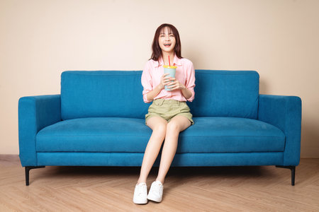 Image of young Asian woman sitting on sofaの写真素材