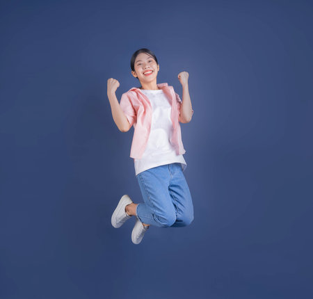 Full length image of young Asian woman standing on background