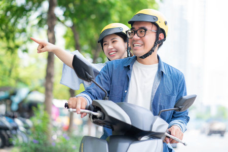 Photo of young Asian couple driving motorbikeの写真素材